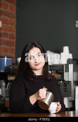 Pretty woman barista making cappuccino Stock Photo