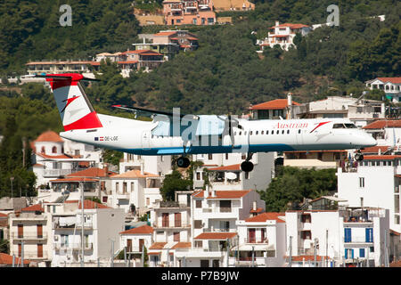 Austrian Airlines Bombardier Dash 8-400 on final at Skiathos airport carrying austrian holidaymakers from Graz with Skiathos Town in the background Stock Photo