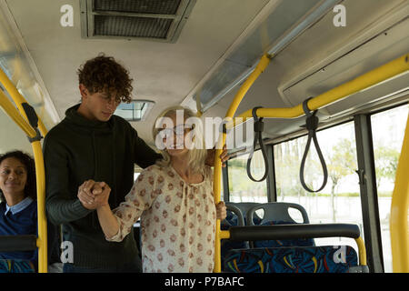 Young man helping senior woman in the bus Stock Photo