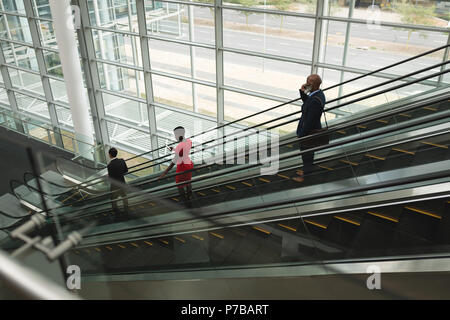 Businesspeople going down on an escalator in the office Stock Photo