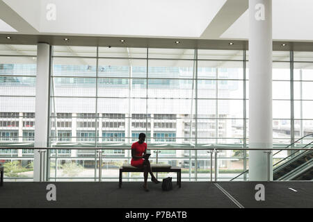 Businesswoman sitting on a bench and using tablet Stock Photo