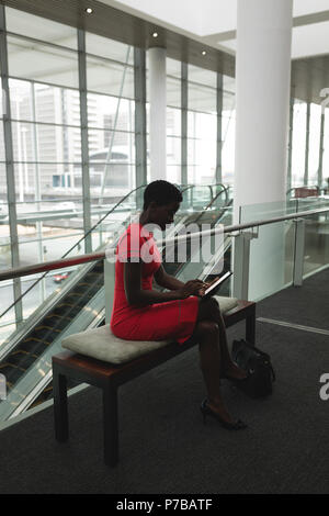 Businesswoman sitting on a bench and using tablet Stock Photo