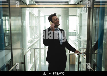 Businessman talking on the phone in elevator Stock Photo