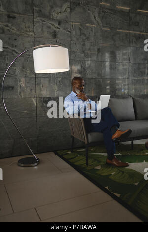 Businessman sitting on the sofa and using laptop Stock Photo
