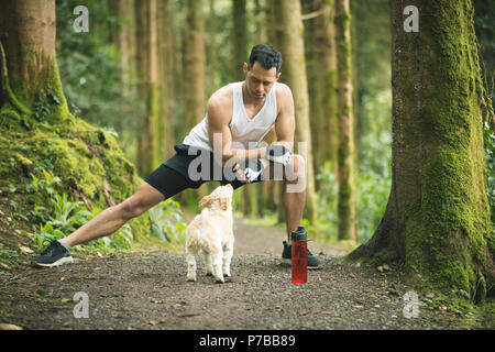 Fit man doing stretching exercise with his dog Stock Photo