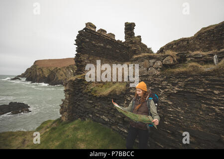 Female hiker leaning against the rock and reading a map Stock Photo