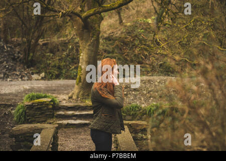 Red hair female hiker looking around in the forest Stock Photo