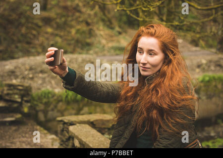 Female hiker taking selfie with mobile phone in the forest Stock Photo