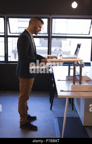 Businessman writing on notepad while using laptop Stock Photo