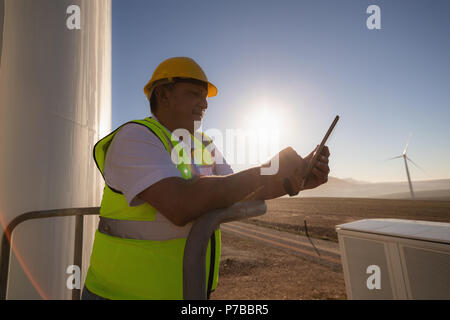 Engineer using a digital tablet at entrance of a wind mill Stock Photo
