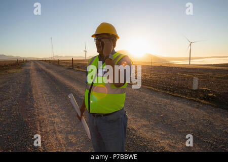 Engineer talking on mobile phone at wind farm Stock Photo