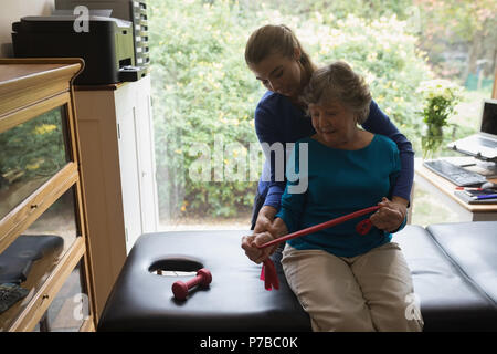 Physiotherapist assisting a senior woman to stretch an elastic band Stock Photo