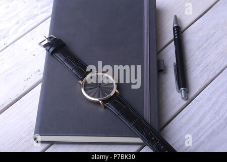 Men's accessories for business and rekreation. Leather notebook, watch and pen on wood background.. Top view composition. Stock Photo