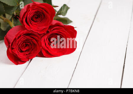 beautiful three red roses on white wooden background Stock Photo