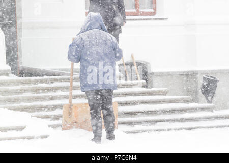 Woman cleaning snow with shovel in winter day. Winter storm Stock Photo