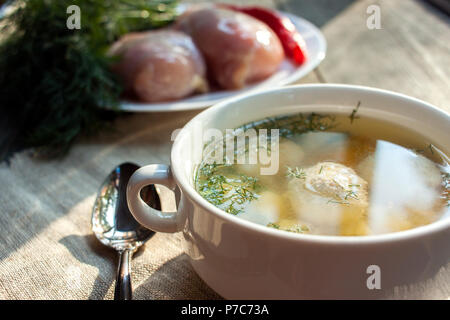Fresh, hot soup with meatballs in a white bowl on a wooden background. Stock Photo