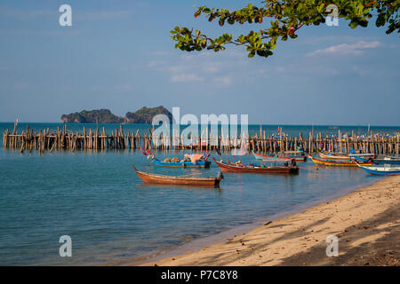 Great scenery of colourful painted wooden fishing boats that are moored near a jetty made of wooden stilts and planks at Pantai Pasir Hitam on... Stock Photo