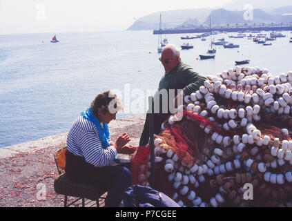Woman sewing fishing nets at the harbour. Castro Urdiales, Cantabria, Spain.
