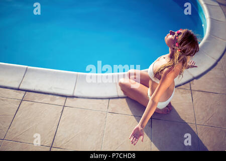 Blond woman meditating at pool Stock Photo