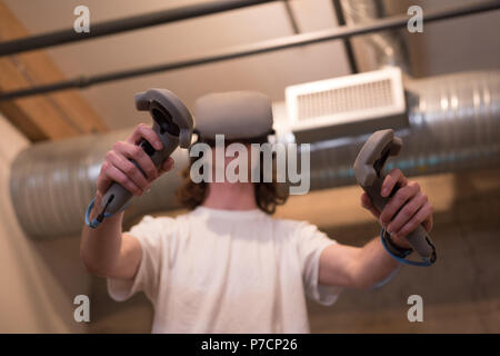 Male executive using virtual reality headset with controller Stock Photo