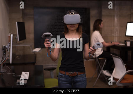 Female executive using virtual reality headset with controller Stock Photo