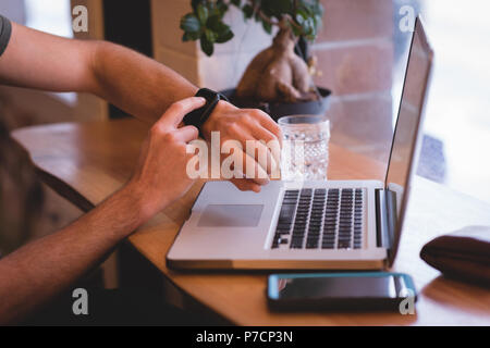 Man using smartwatch in cafe Stock Photo