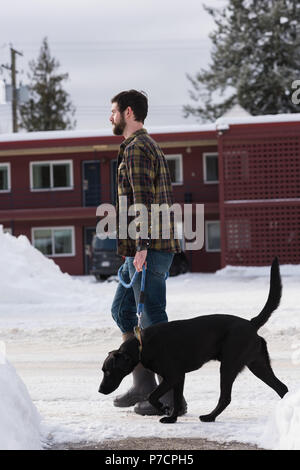 Man walking with his dog on sidewalk Stock Photo