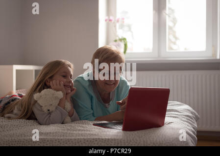 Grandmother and daughter using laptop in bedroom Stock Photo