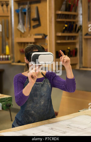 Female carpenter using virtual reality headset Stock Photo