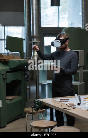 Male carpenter with digital tablet using virtual reality headset Stock Photo
