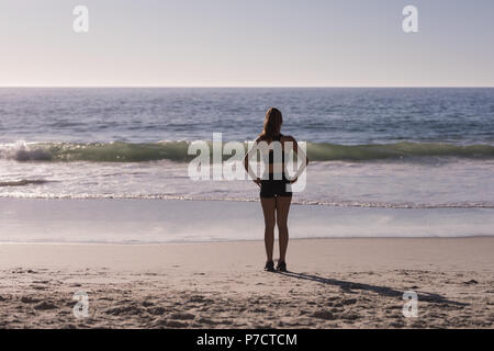 Fit woman standing with hands on hip in the beach Stock Photo