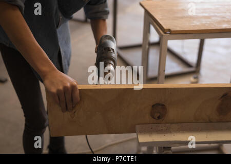 Female welder using drilling machine in workshop Stock Photo