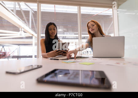 Female executives using digital tablet and laptop at desk Stock Photo