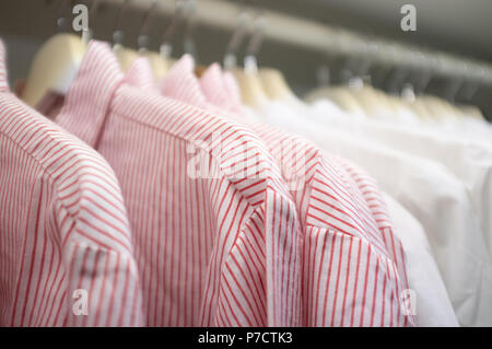Striped business shirts on hangers in a wardrobe with shallow focus Stock Photo