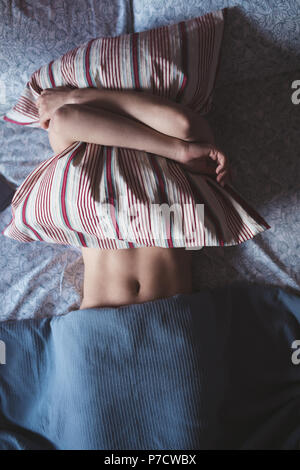 Woman embracing pillow while sleeping in bedroom Stock Photo