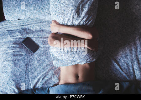 Woman embracing pillow while sleeping in bedroom Stock Photo