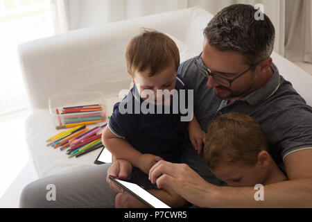 Father with his sons using digital tablet in living room Stock Photo