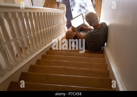 Senior man using laptop on stairs Stock Photo