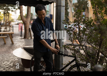 Businessman locks his bicycle on the pole Stock Photo