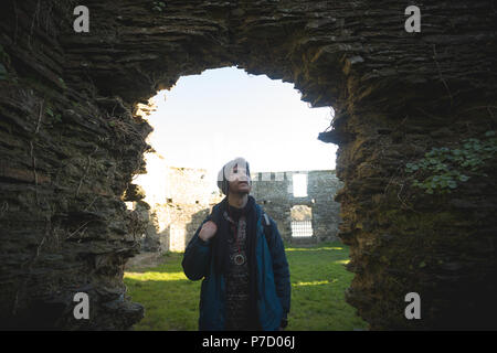 Male hiker standing at old ruin in countryside Stock Photo