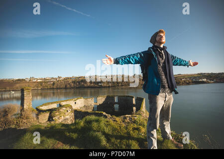 Male hiker standing with arms outstretched in countryside Stock Photo