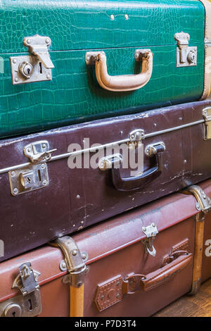 Stacked old green, brown and tan leather suitcases, background image Stock Photo