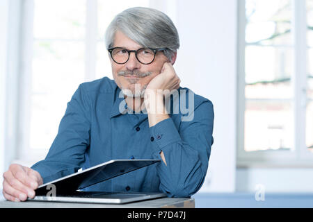 Man with laptop leaning on a desk Stock Photo