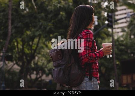 Woman with coffee cup standing on street Stock Photo