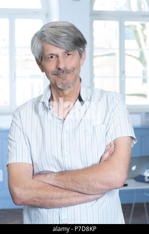Man standing in his office with his arms crossed Stock Photo