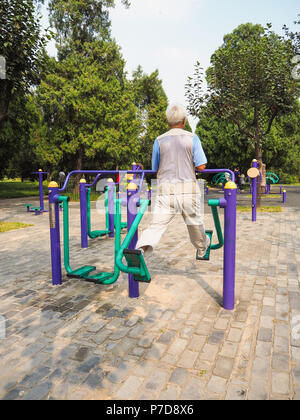 Older man working out on the public equipment in the park of the Temple of Heaven, Beijing Stock Photo