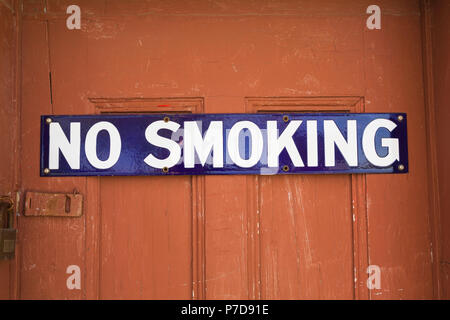 White and blue No Smoking sign on reddish brown wooden entrance door, Quebec, Canada Stock Photo