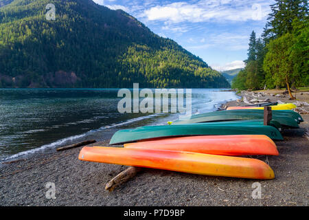 Row of colorful kayaks lying on the shore of Lake Crescent on late afternoon, Olympic National Park, Washington State, USA. Stock Photo