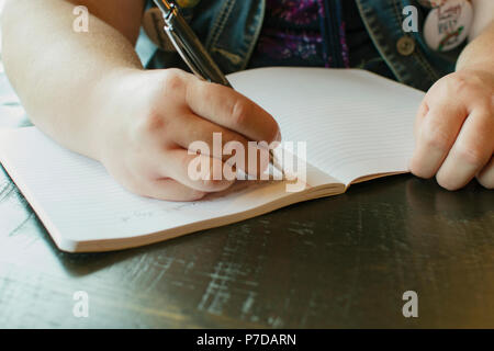 Student writing in a note book with a Pen. Stock Photo