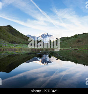 snow capped mountain reflected in water of small lake near col de vars in french alps Stock Photo